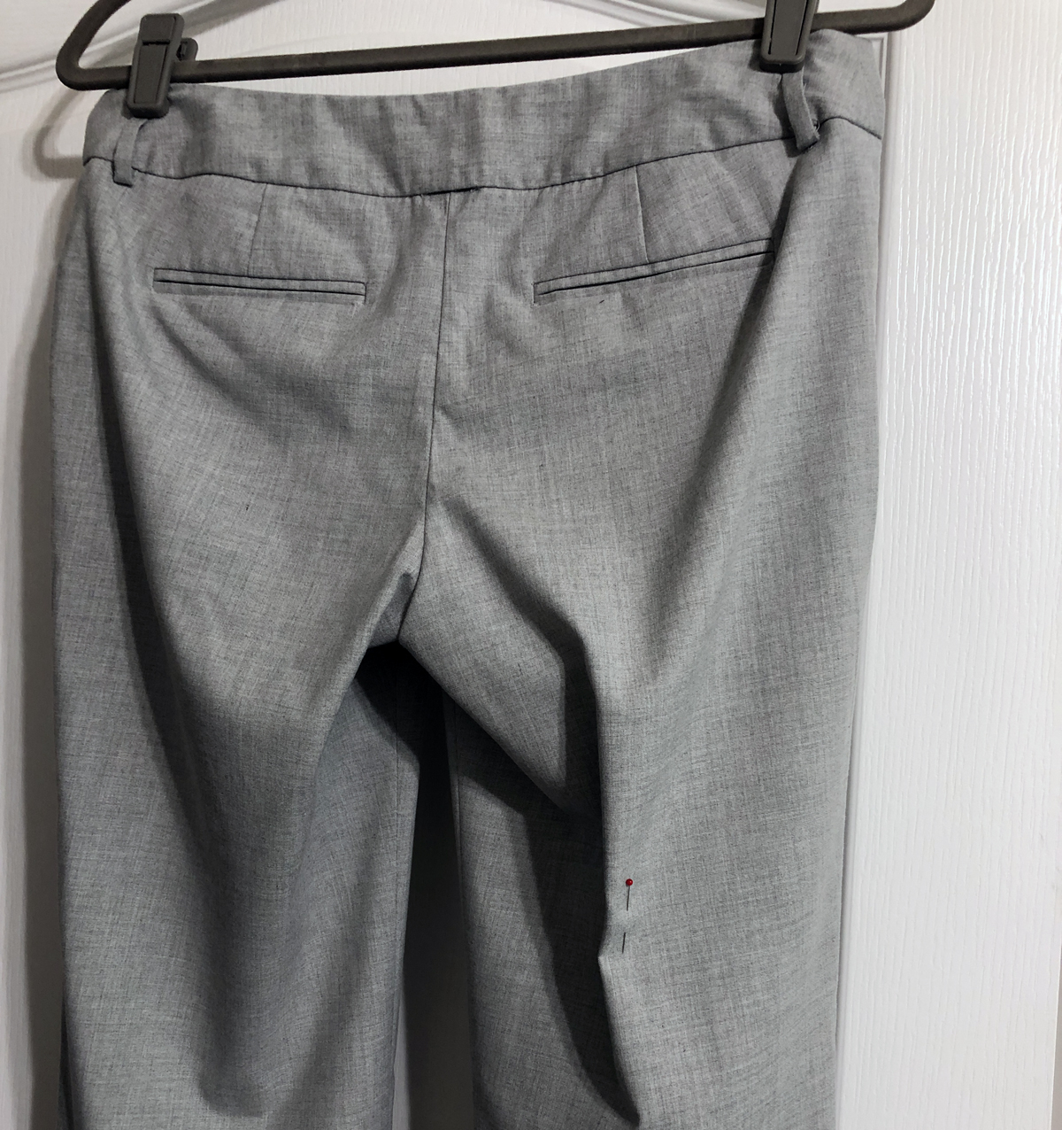 Pin placed vertically on back leg of women's gray menswear-look trousers