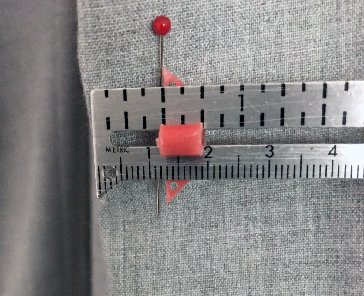 Seam gauge measuring from fold to pin on women's gray pants