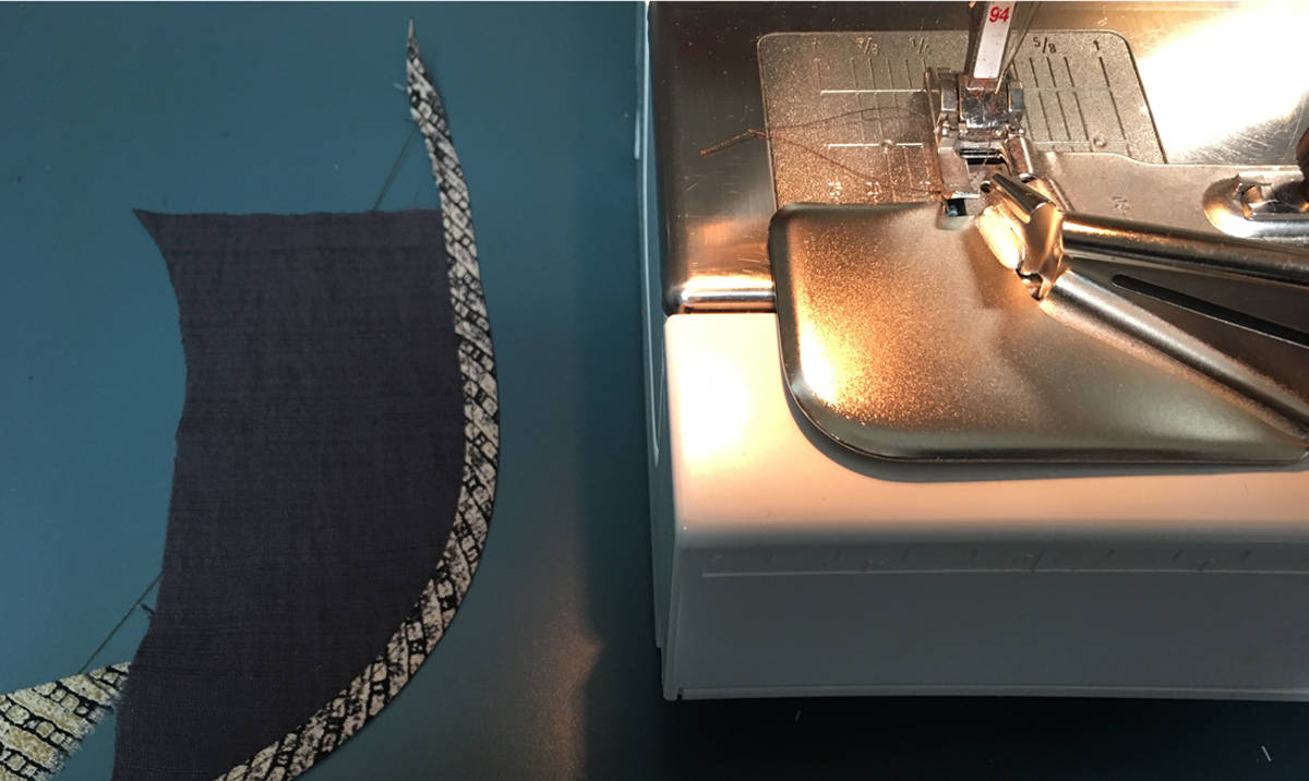 Bound fabric scrap lying near sewing machine with binding foot attached