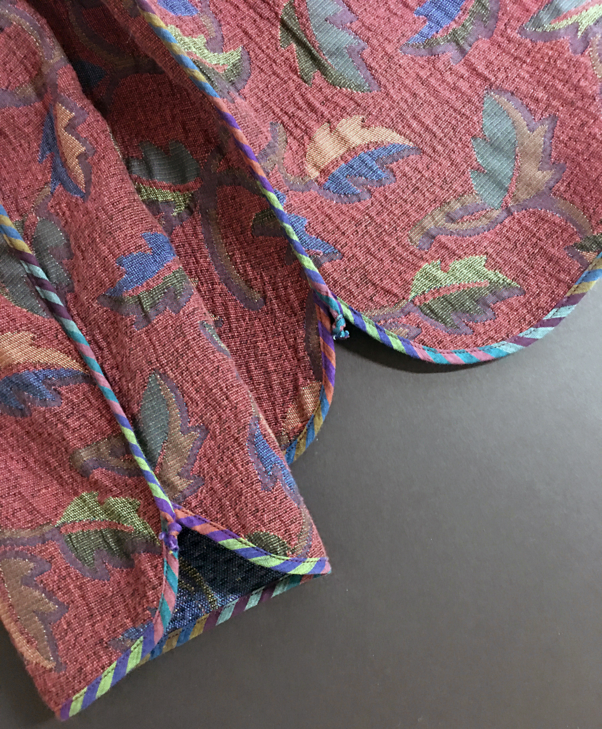 Closeup of finished reversible jacket with striped bias strip binding around sleeve and jacket hems