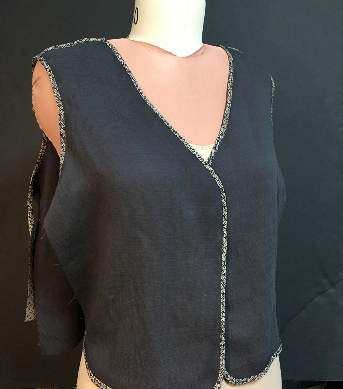 Unfinished gray vest on dress form showing bound front and neckline edge