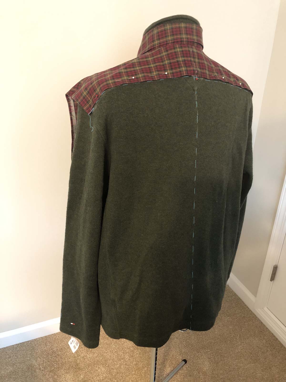 Red plaid shirt laid on top of olive green sweater on dress from