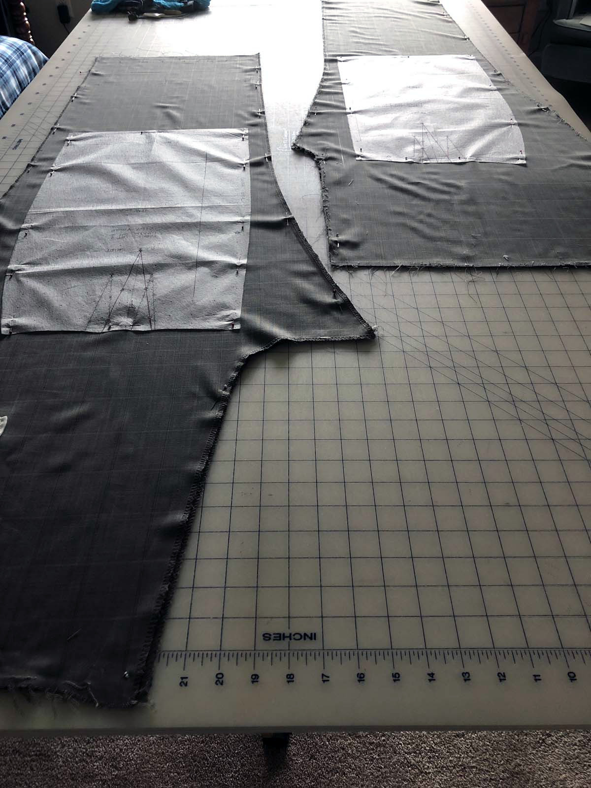 Deconstructed men's suit pant legs laid out with skirt patterns pinned on top 