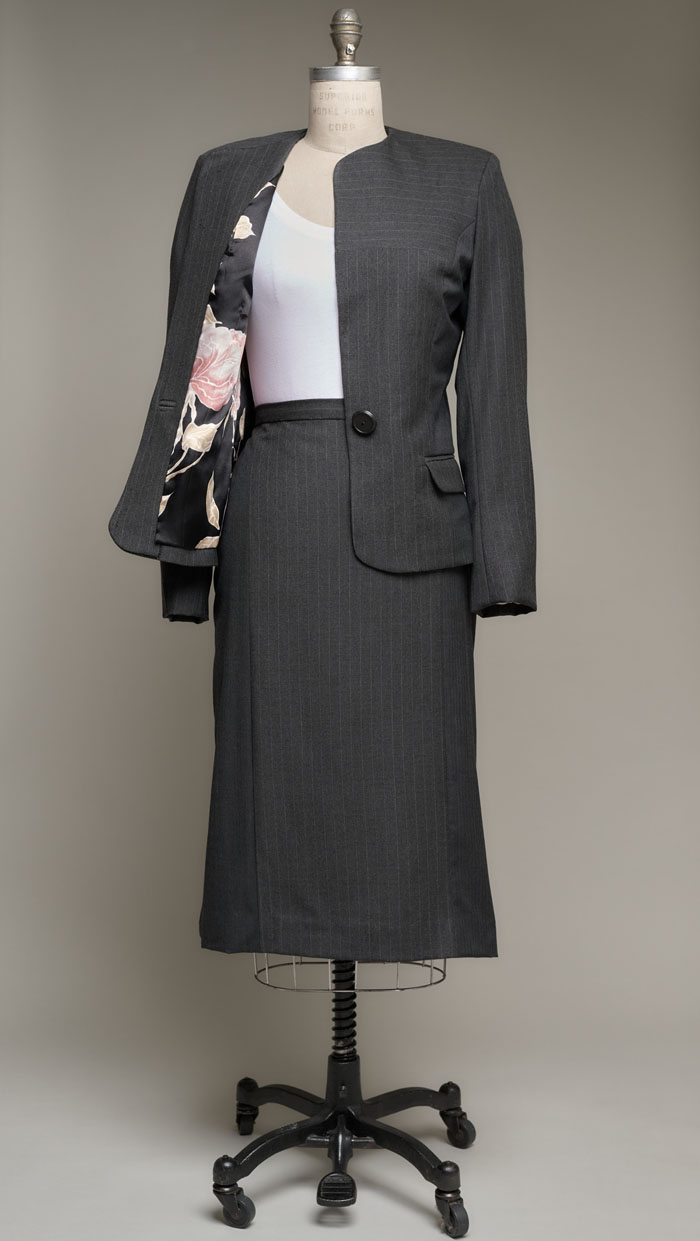 Women's suit on dress form, jacket opened to reveal colorful lining