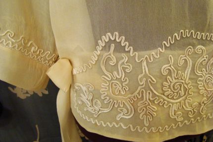 The soutache is applied to the silk with stitches along one edge, so the braid stands on end