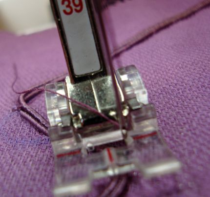 Sewing a section by machine using a clear appliqué foot and a blind hem stitch.