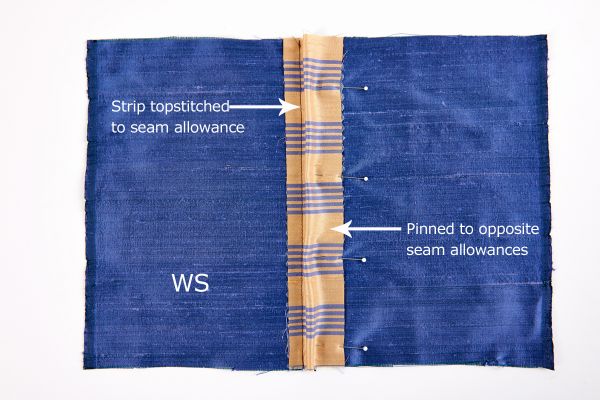 Center the underlay strip, right side down, over the seam allowances (aligning the raw edges), and pin.